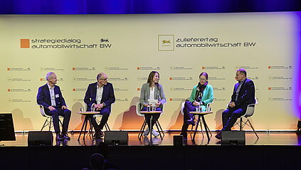 Fünf Personen sitzen auf dem Podium zu einer Diskussionsrunde. 